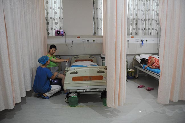 Phòng chờ sinh ở Trung Quốc cũng có khoảng 3-4 giường, được ngăn cách bởi cách tấm rèm kéo bằng vải mỏng. Trong phòng chờ sinh, thai phụ 9x Guo Jia đang bắt đầu được y tá hướng dẫn ngồi trên quả bóng sinh để luyện tập
