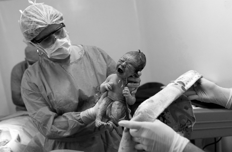 Em bé sau khi chào đời được bác sĩ trao cho y tá để vệ sinh...
